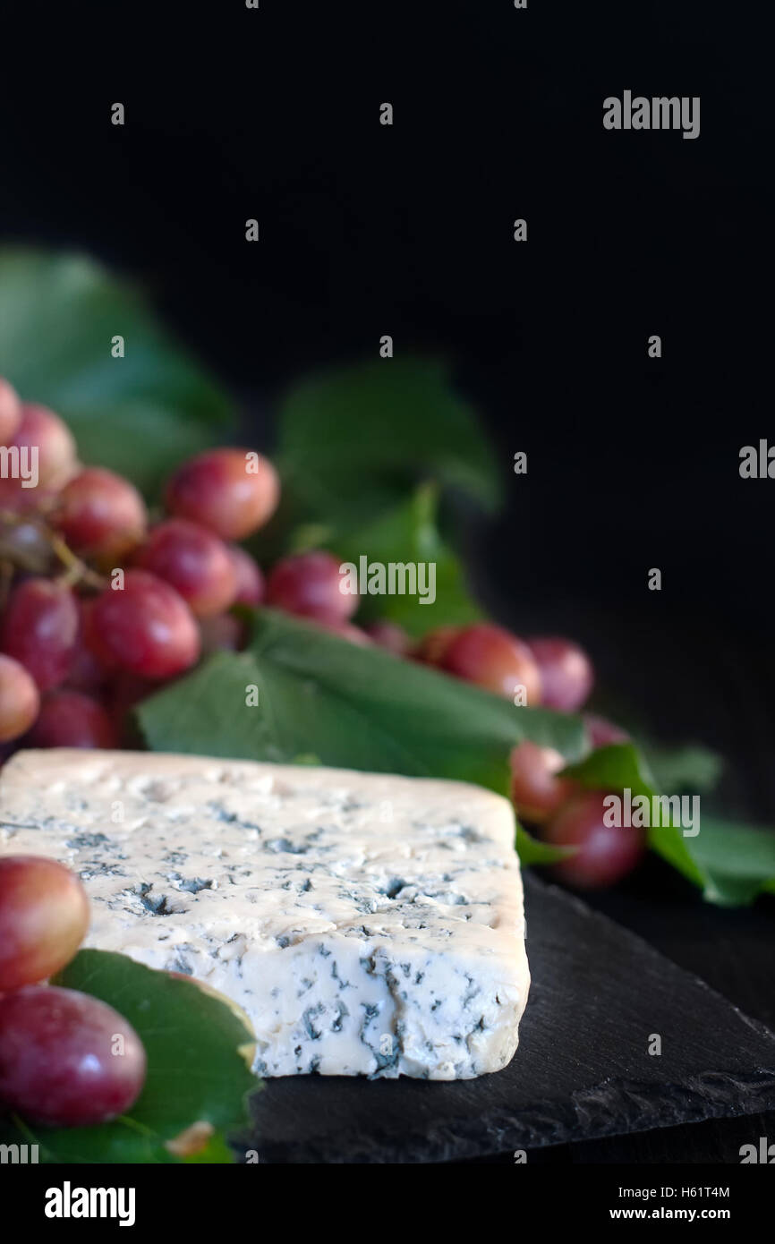 Formaggio blu Dorblu con uva rossa su sfondo nero Foto Stock