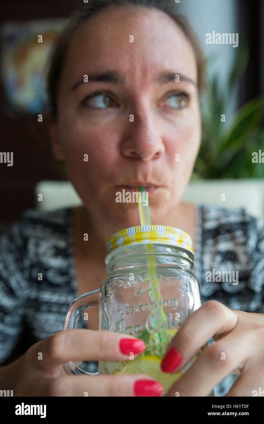 Le donne di bere una bevanda rinfrescante, donna trattiene il vaso e bevanda attraverso la paglia Foto Stock