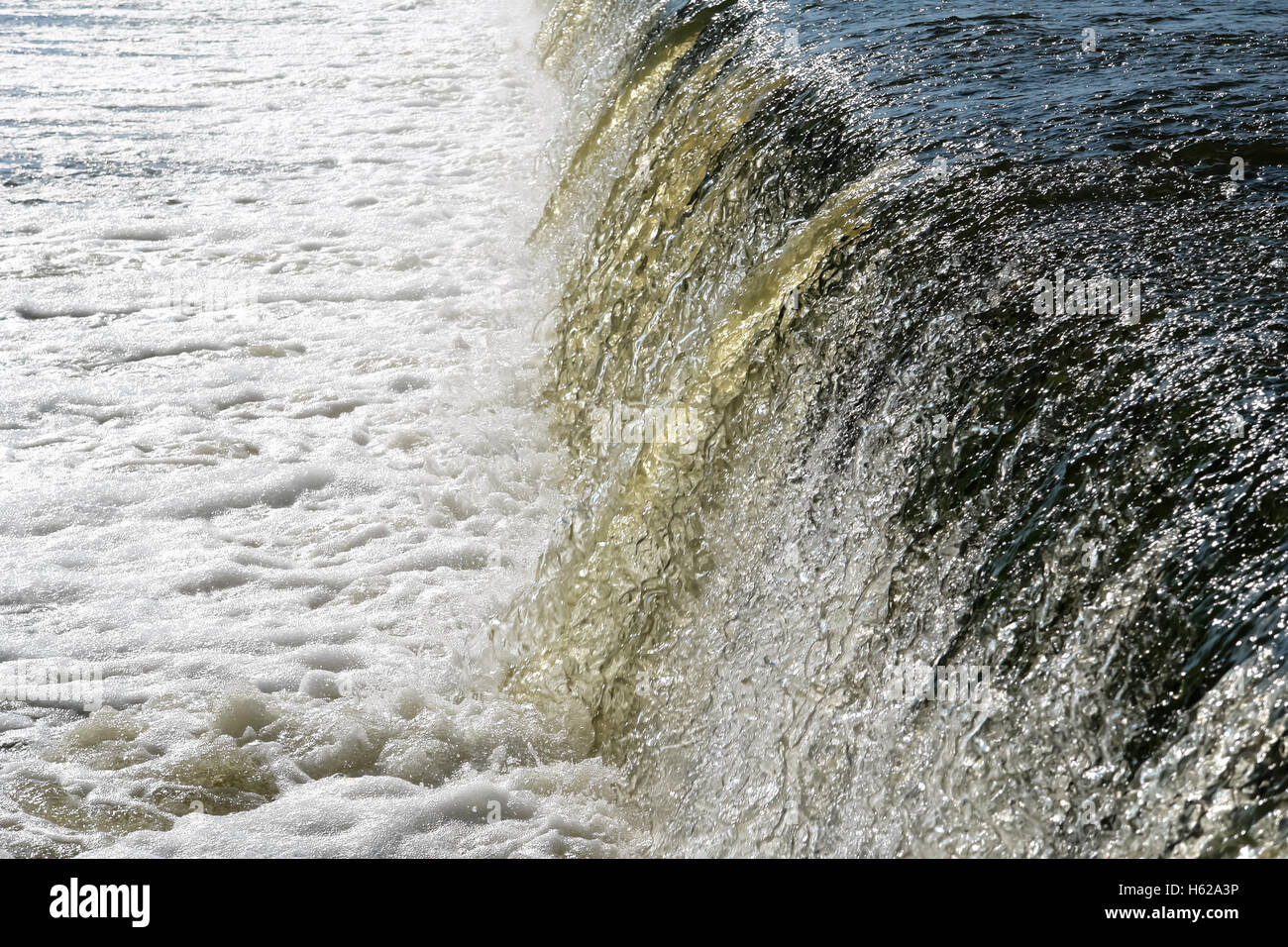 Vista della caduta di acqua sulla diga di pietra. Foto Stock