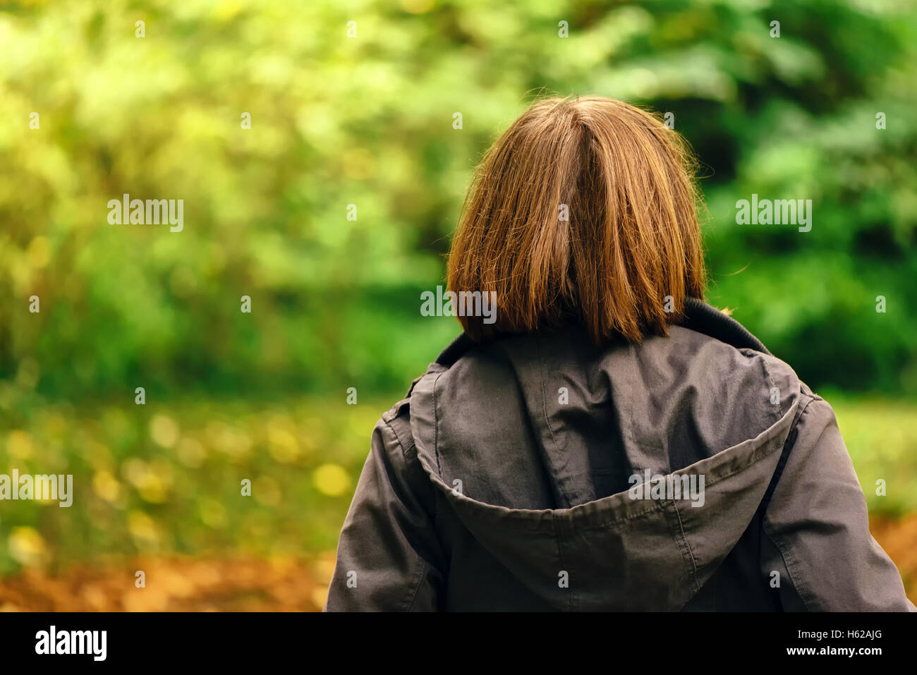 Vista posteriore del casual donna camminando in autunno o parco foresta, donna in caduta stagione ambiente scenario da dietro Foto Stock
