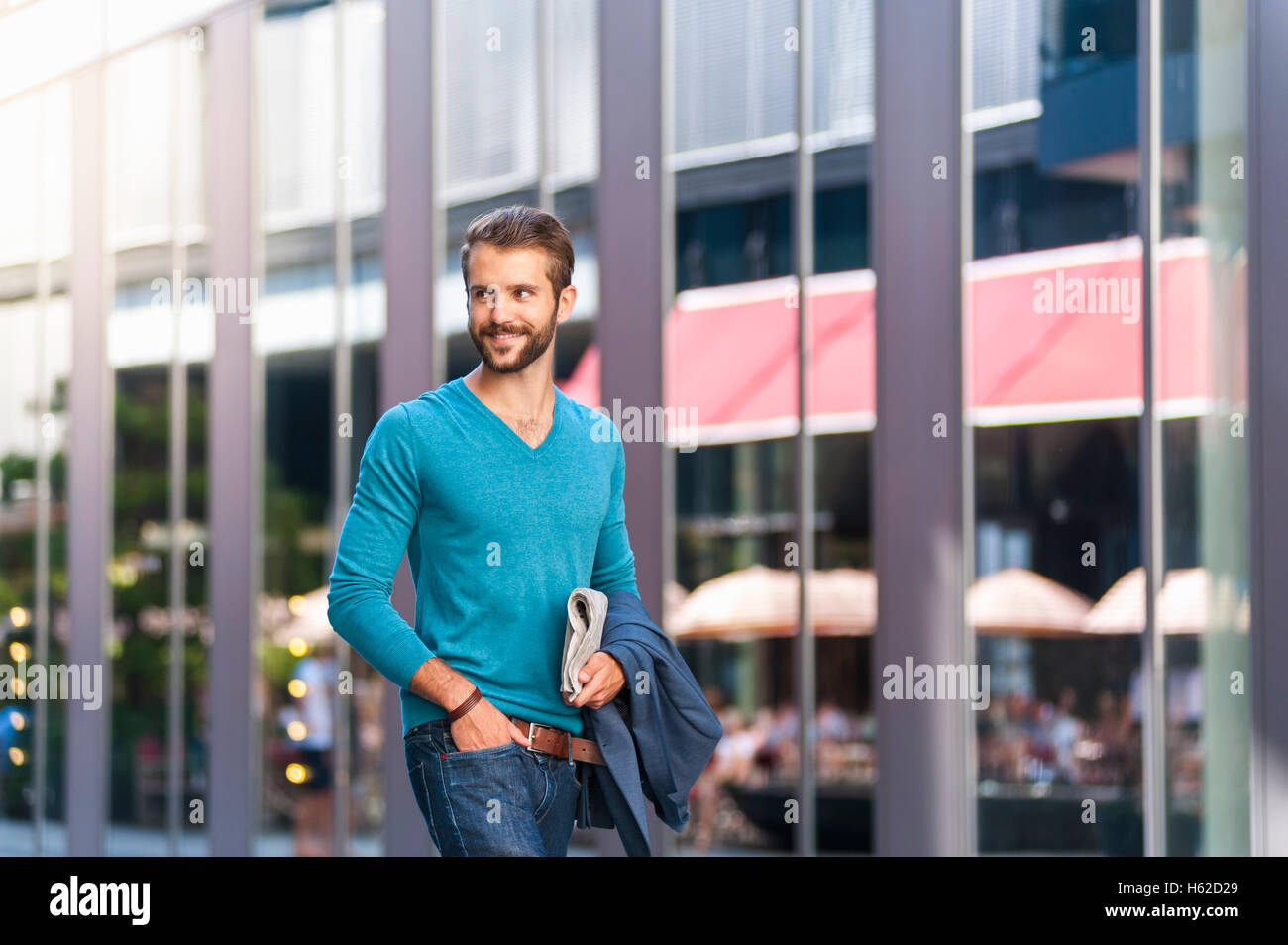 Sorridente giovane azienda giornale passeggiate in città Foto Stock