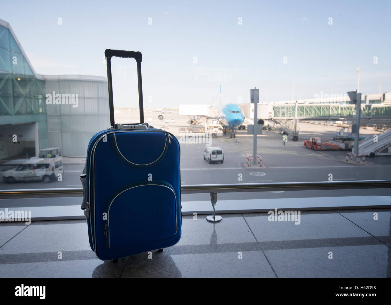 Valigia blu all'aeroporto, in aereo in background Foto Stock