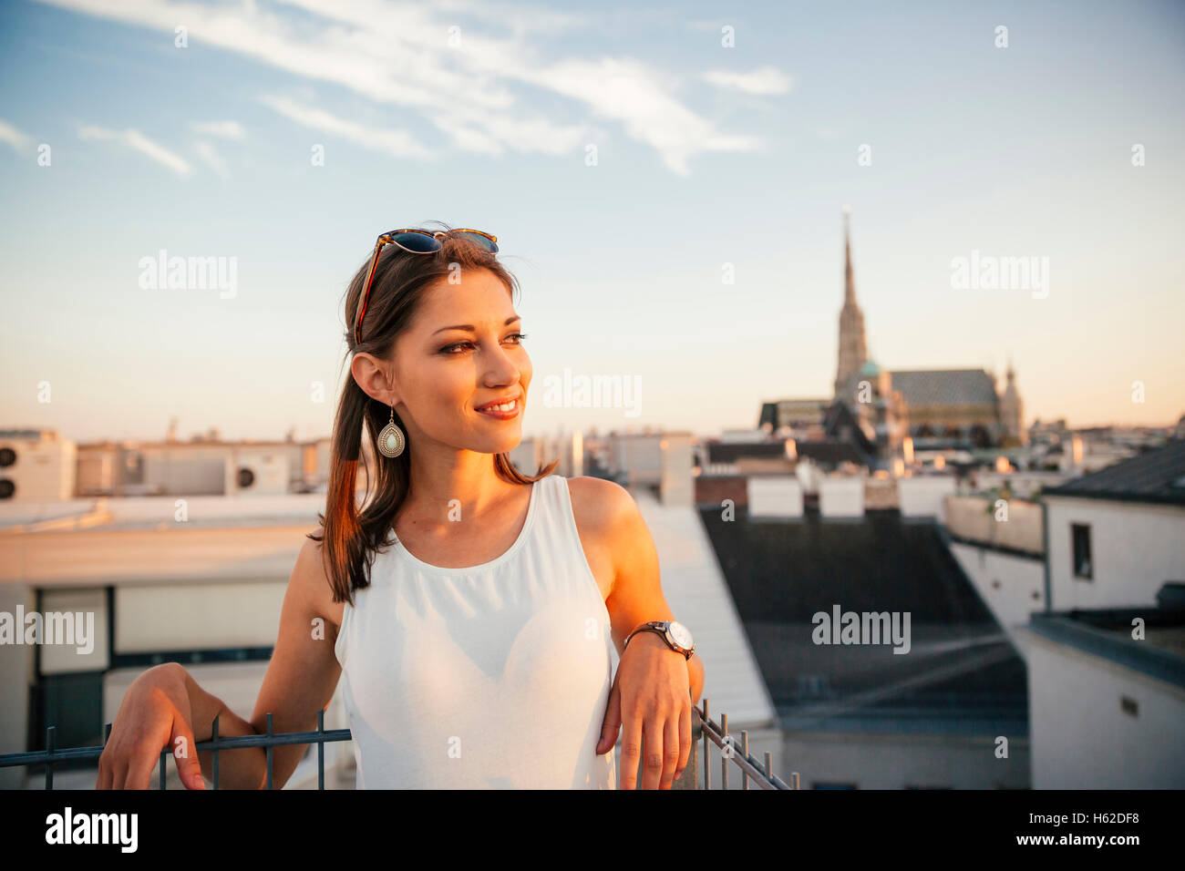 Austria, Vienna, ritratto di sorridere giovane donna sul tetto al tramonto con il Stephansdom in background Foto Stock