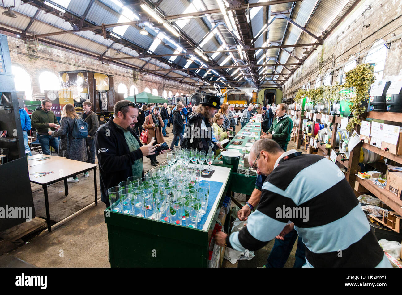 CAMRA beer festival nel vecchio capannone locomotiva a Tunbridge Wells, Regno Unito. La gente la selezione di birre provenienti da vari fusti, barili di birra, a lungo dietro un contatore. Foto Stock