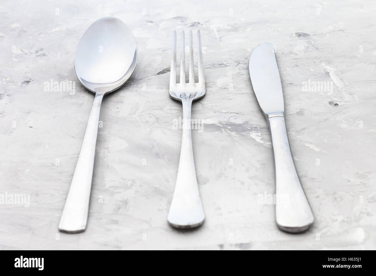 Concetto di cibo - servizio di set da tavola coltello, forchetta, cucchiaio Zuppa su una superficie in calcestruzzo Foto Stock