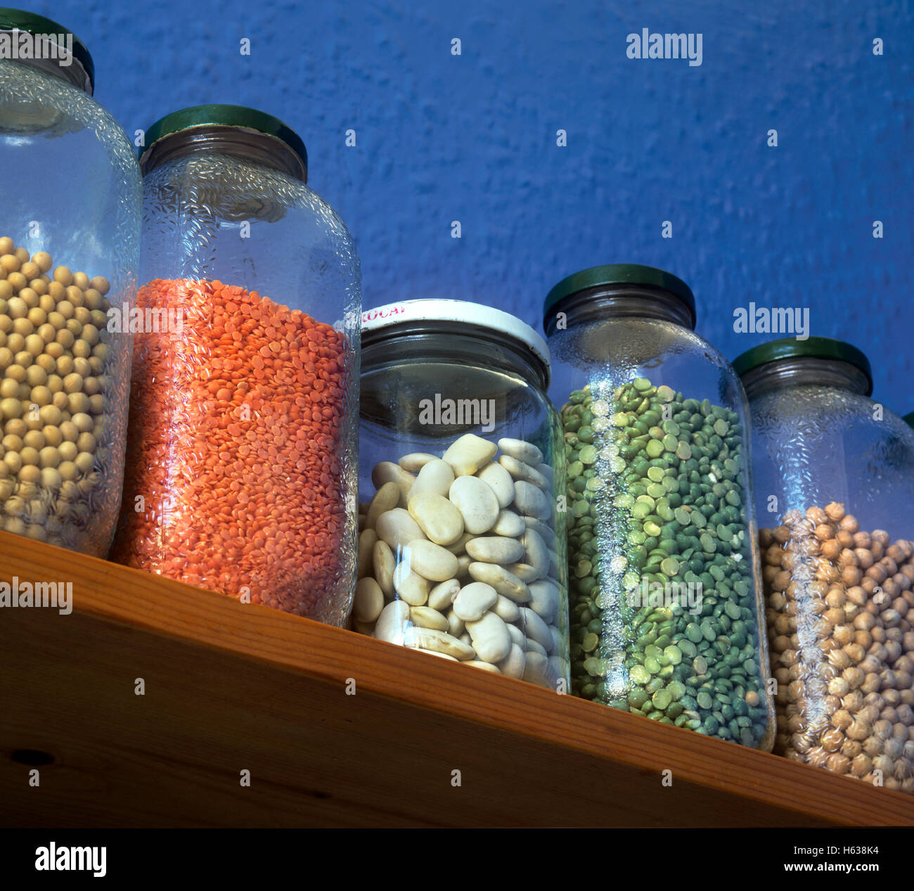 Impulsi in vasi di deposito su un ripiano della cucina. Da sinistra: i semi di soia, di lenticchie rosse, il burro I fagioli, verde split piselli, ceci. Foto Stock