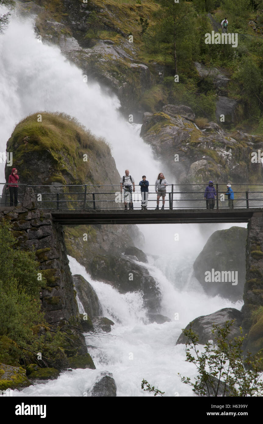 Turisti sul ponte attraverso Kleivafossen cascata a valle dal Ghiacciaio Briksdal, Briksdal valley, Jostedalsbreen national park, Norvegia. Foto Stock