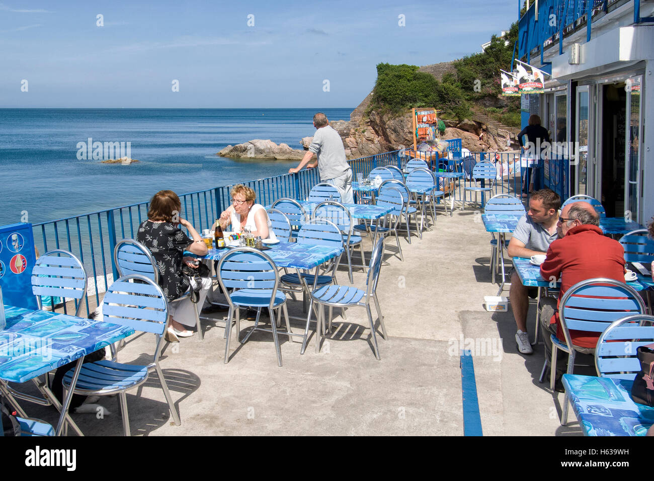 I turisti piace mangiare al fresco presso un bar sulla spiaggia in brixham devon, su una soleggiata giornata estiva. Foto Stock