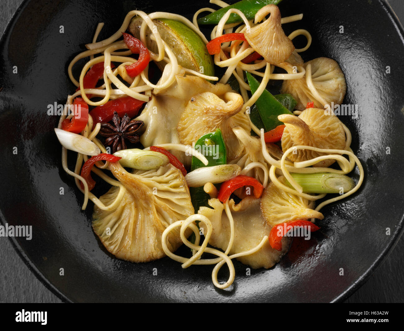 Giallo funghi Oyster stir fry essendo cotti con tagliatelle, gestire tout, pepe rosso, cipolline e avviare l'anice Foto Stock