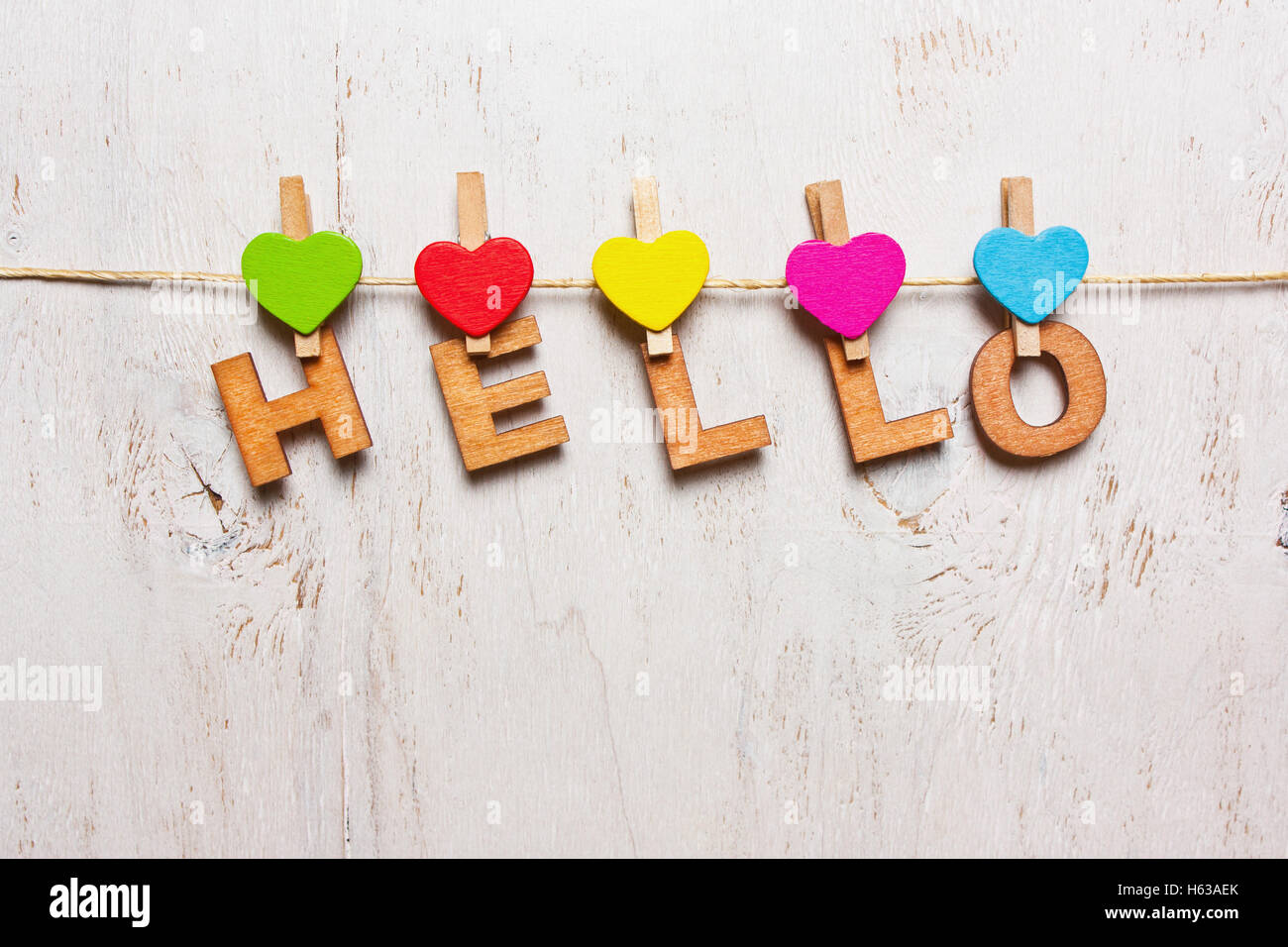 La parola "hello" dalle lettere di legno su un clothespin su uno sfondo bianco antico Foto Stock