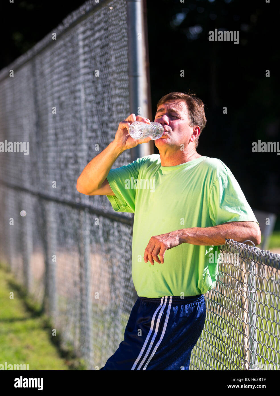 Maschio adulto prendendo una pausa dal jogging di bere acqua Foto Stock