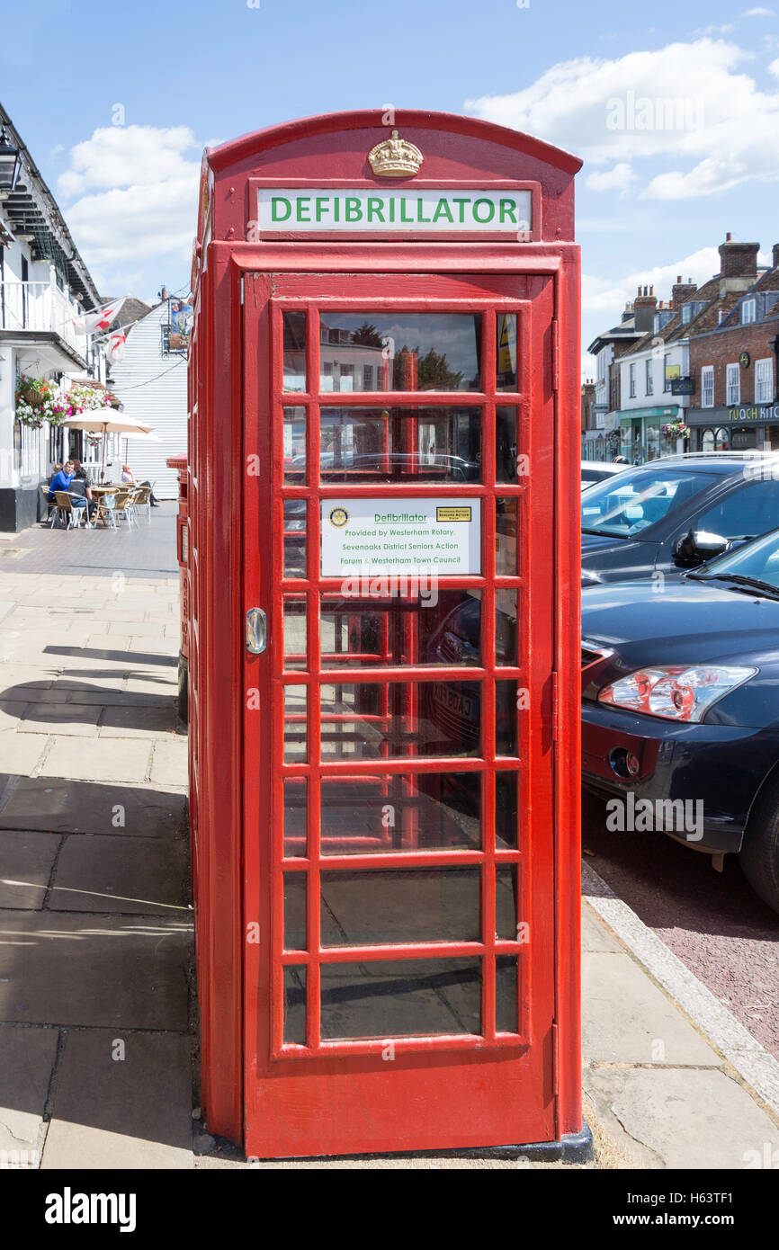 Telefono rosso kiosk con all'interno del defibrillatore, High Street, Westerham, Kent, England, Regno Unito Foto Stock