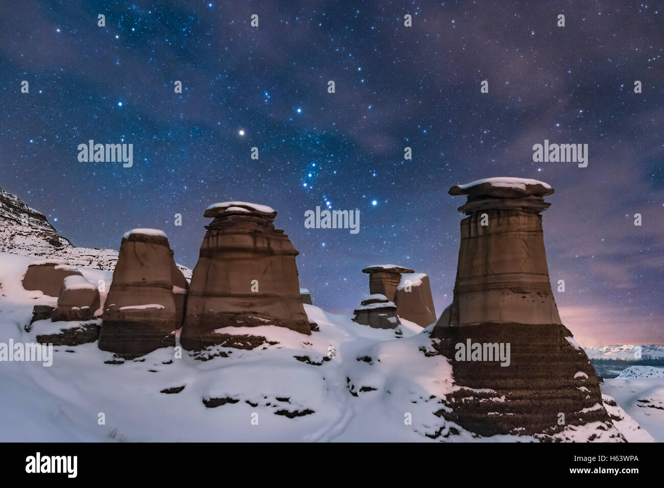 Orion sorge dietro le hoodoos iconica sulla Highway 10 est di Drumheller, Alberta, vicino Oriente Coulee, su un gennaio senza luna di notte, Foto Stock