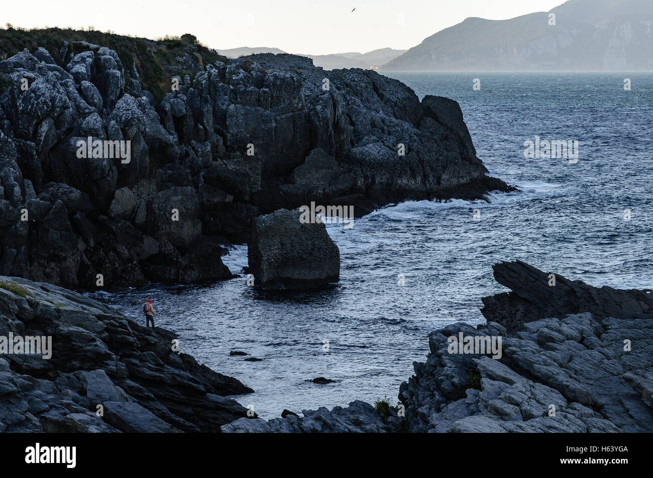 Uno dei pescatori con le loro aste on the rocks, il fondo del mare, costiera nel nord della Cantabria, SPAGNA Foto Stock