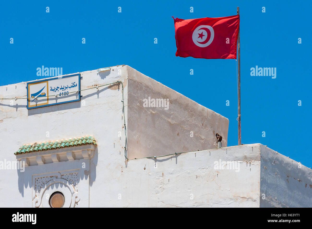 Bandiera Nazionale della Tunisia volare al di sopra di un edificio bianco Foto Stock