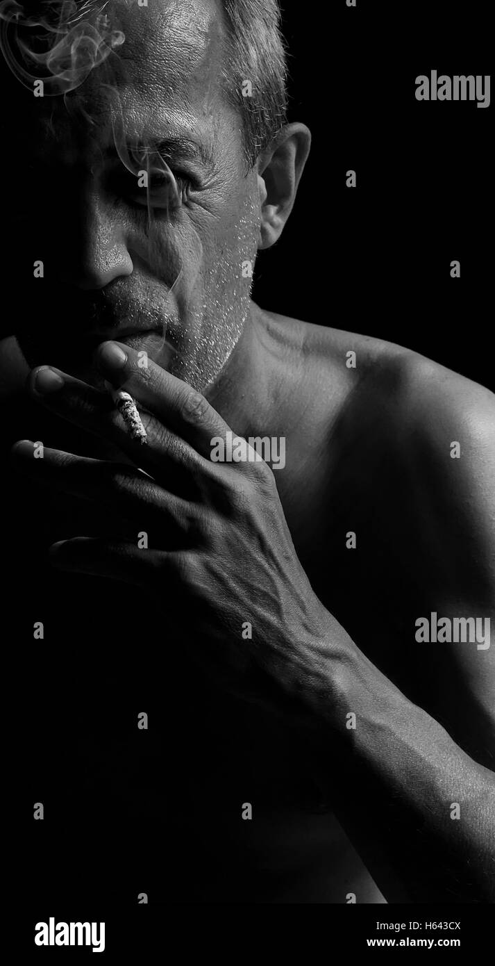 Un uomo con una sigaretta nel buio. Foto Stock