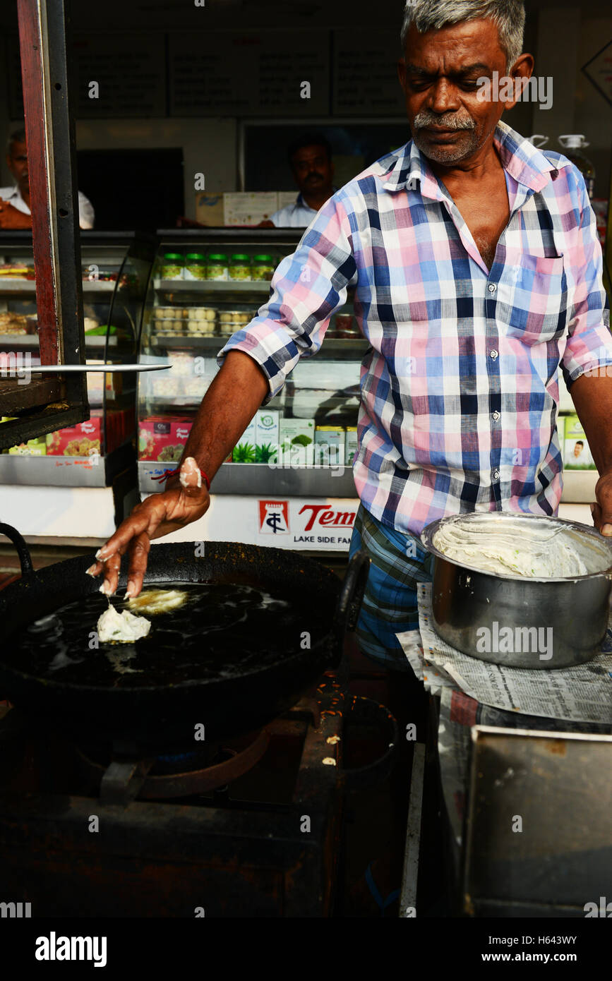 Un cuoco preparare Medu vada in un cibo di strada stallo in Tamil Nadu, India. Foto Stock