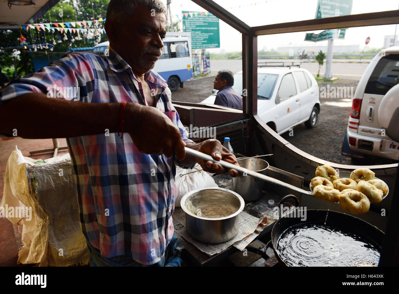 Un cuoco preparare Medu vada in un cibo di strada stallo in Tamil Nadu, India. Foto Stock