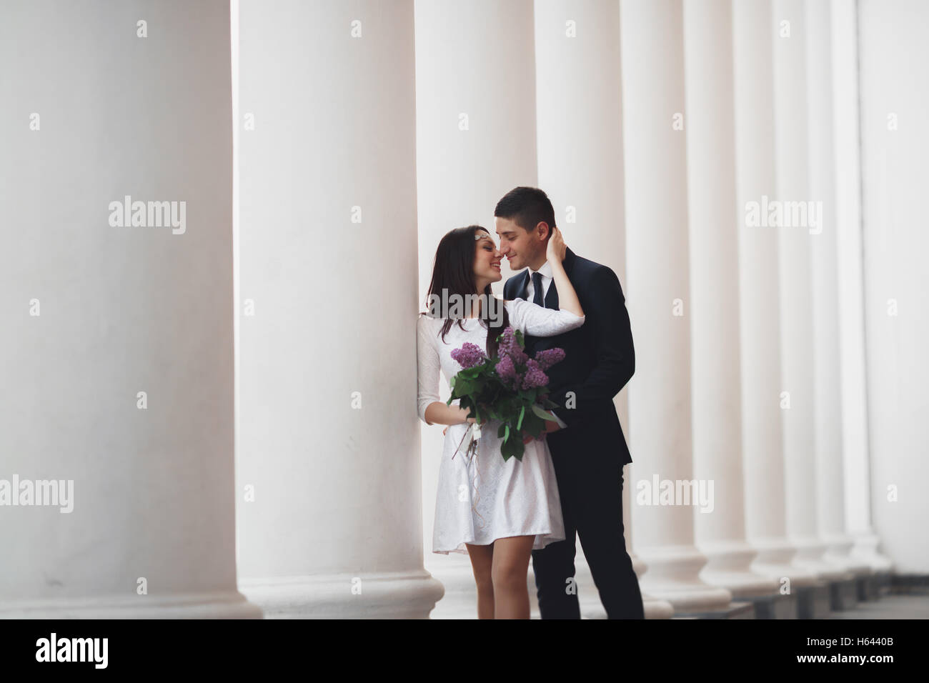 Bella giovane, la sposa e lo sposo in posa vicino al grande colonna bianca Foto Stock