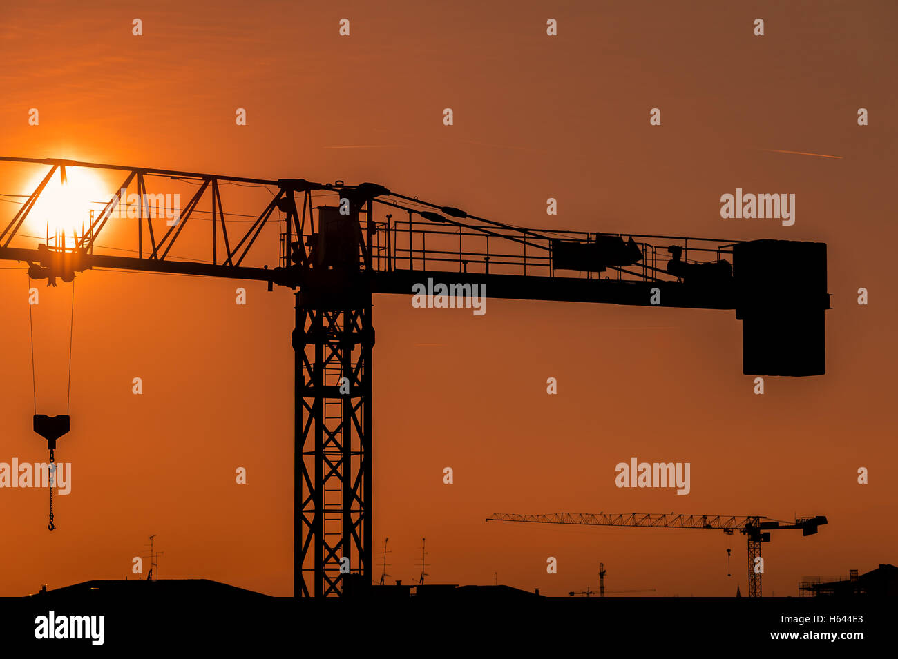 Gru a torre su un sito in costruzione al tramonto o l'alba Foto Stock