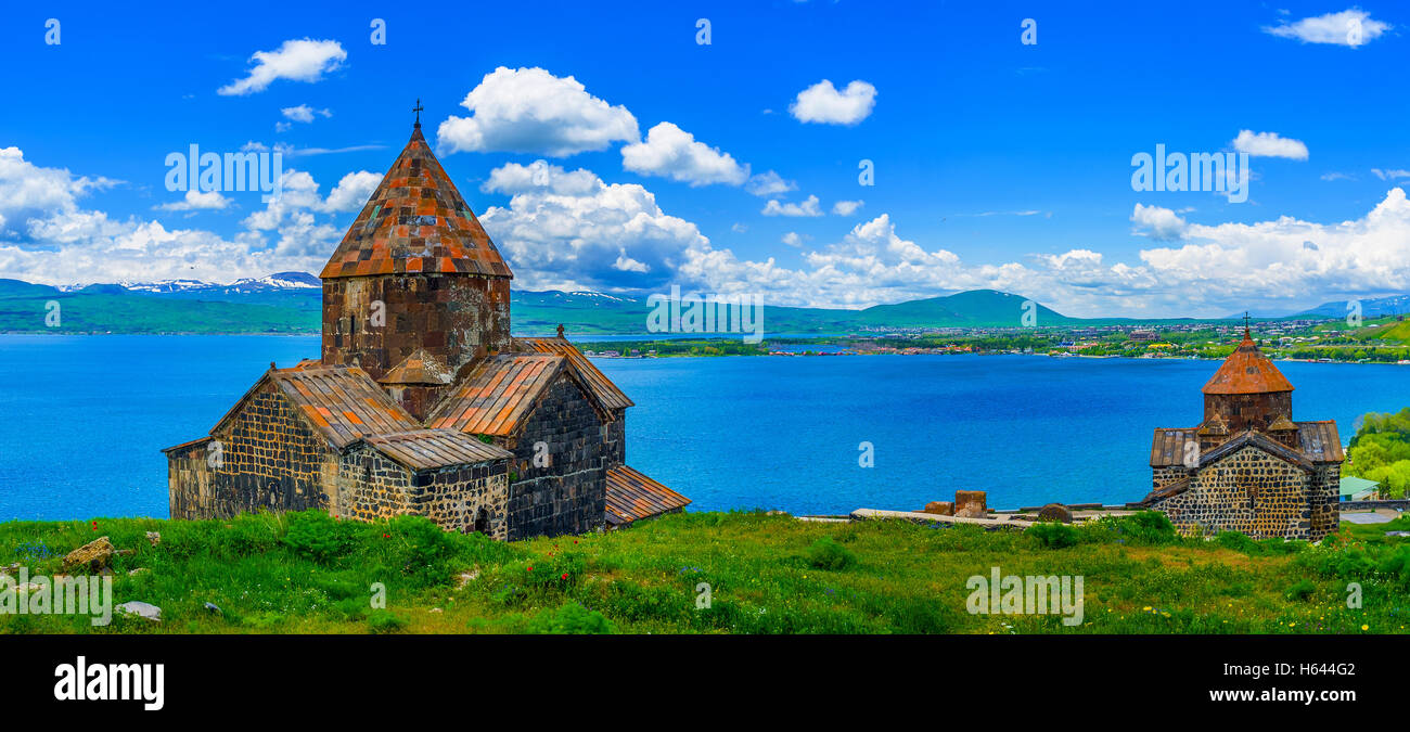 Vista panoramica della penisola di Sevan con entrambe le Chiese del Monastero Sevanavank - Santi Apostoli e la Santa Madre di Dio, sul prato Foto Stock