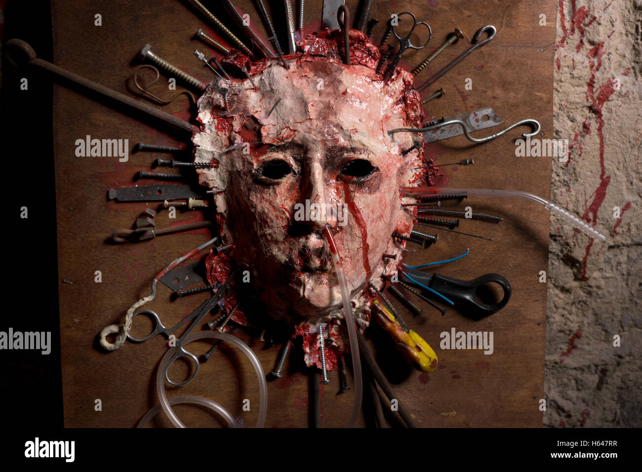 In prossimità di una sanguinosa scuoiate volto di una persona distesa aperta su una tavola di legno con un assortimento di armi taglienti a fianco di un sangue spl Foto Stock