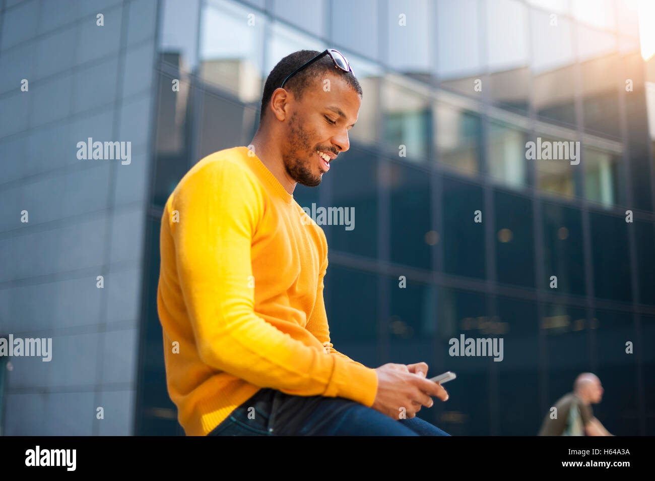 Ritratto di uomo sorridente indossare pullover di colore giallo per la messaggistica di testo Foto Stock