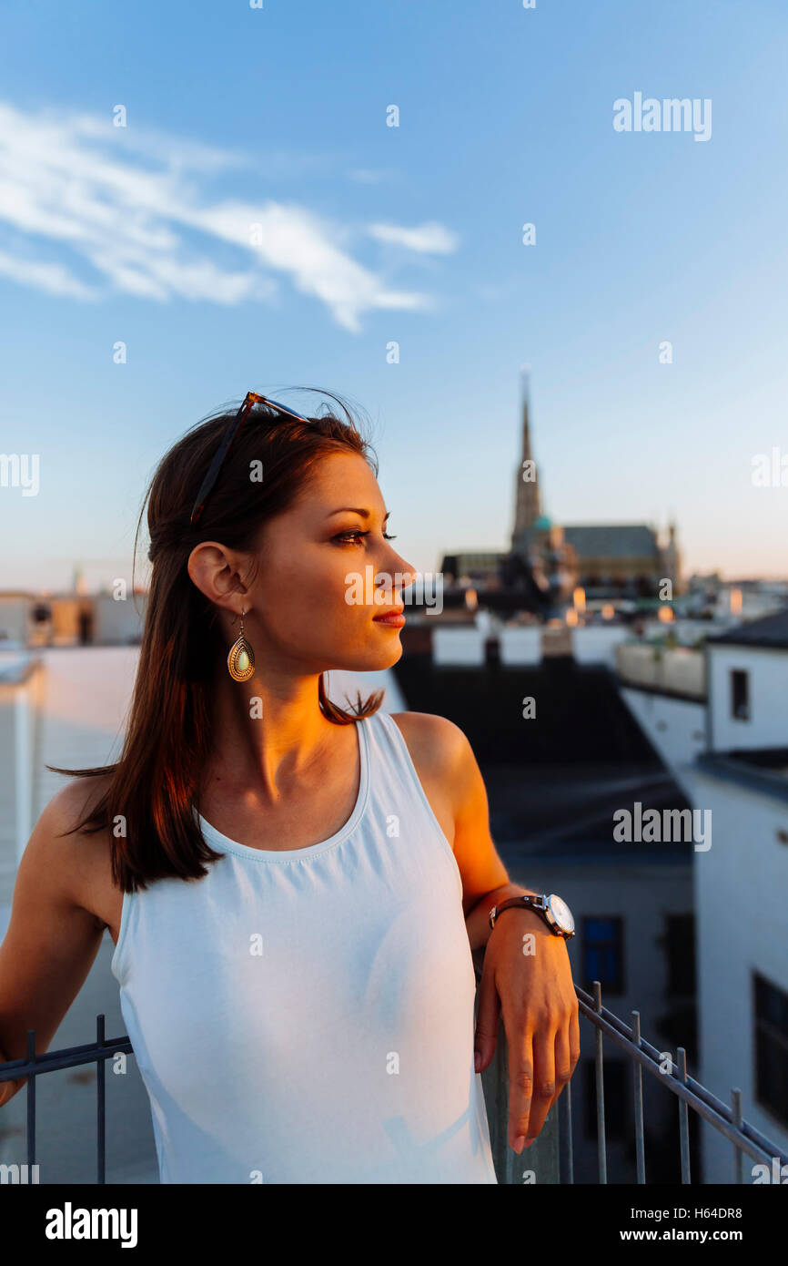 Austria, Vienna, giovane donna sul tetto al tramonto con il Stephansdom in background Foto Stock