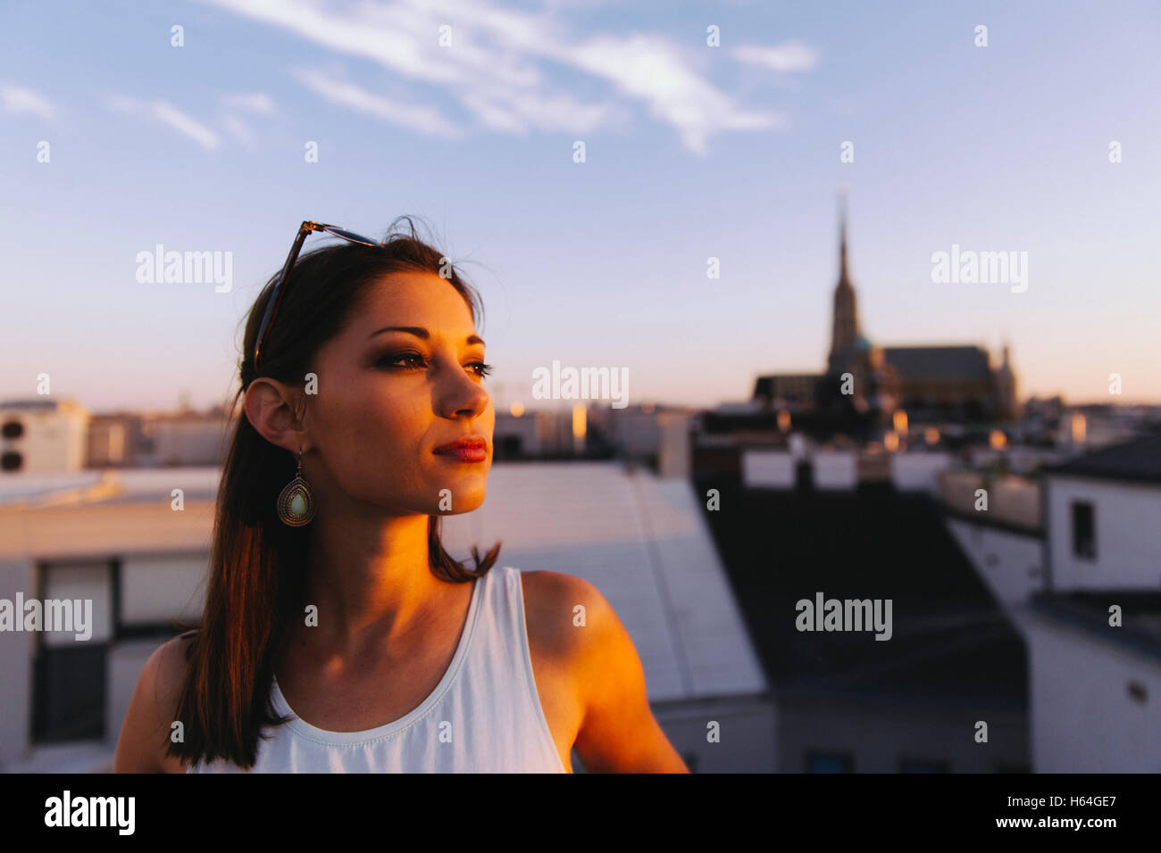 Austria, Vienna, giovane donna rilassante sul tetto al tramonto con il Stephansdom in background Foto Stock