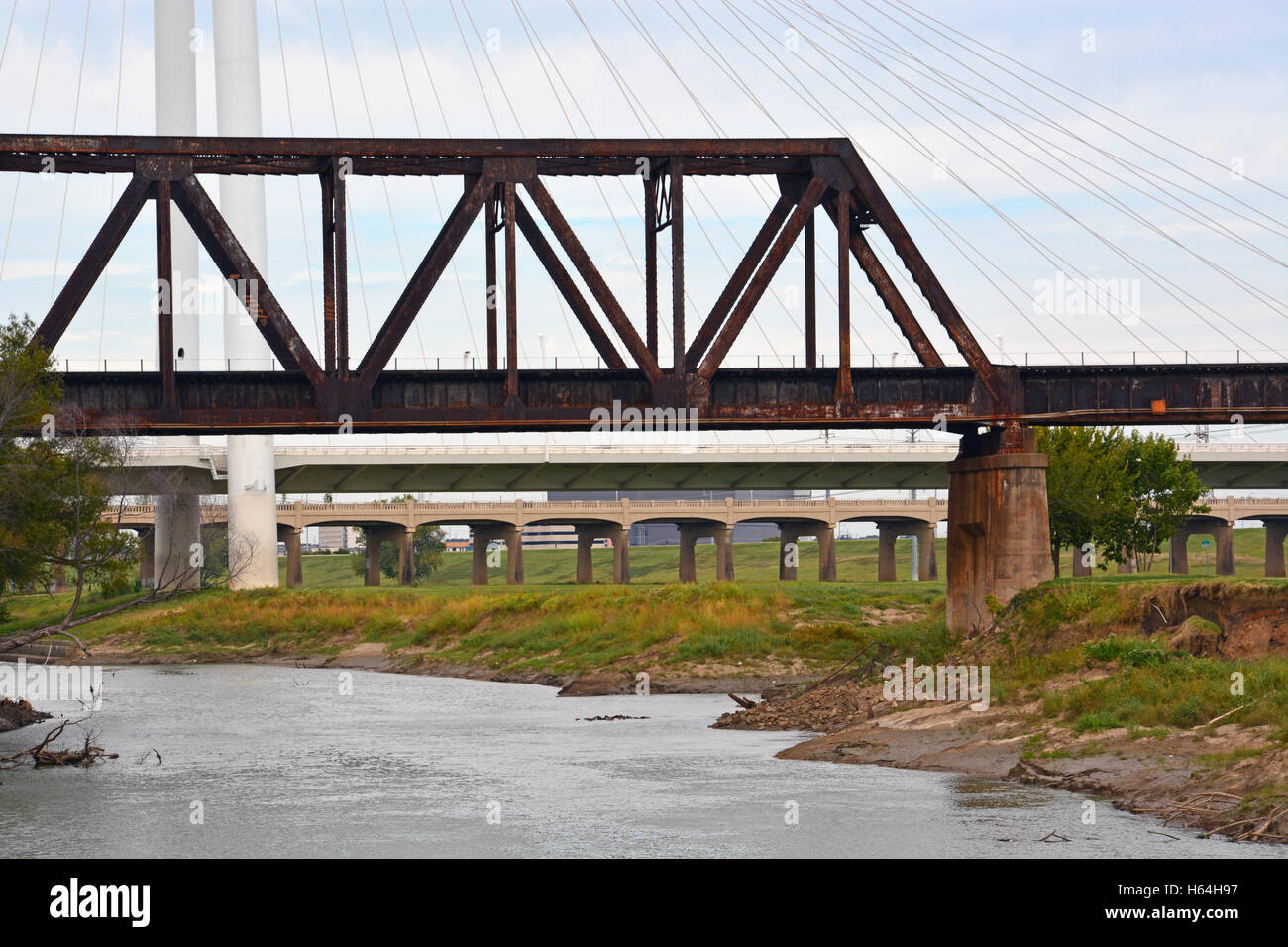 Traliccio in acciaio railroad, cavo automobile, e calcestruzzo ponte pedonale forniscono accesso a downtown Dallas oltre il fiume della Trinità. Foto Stock