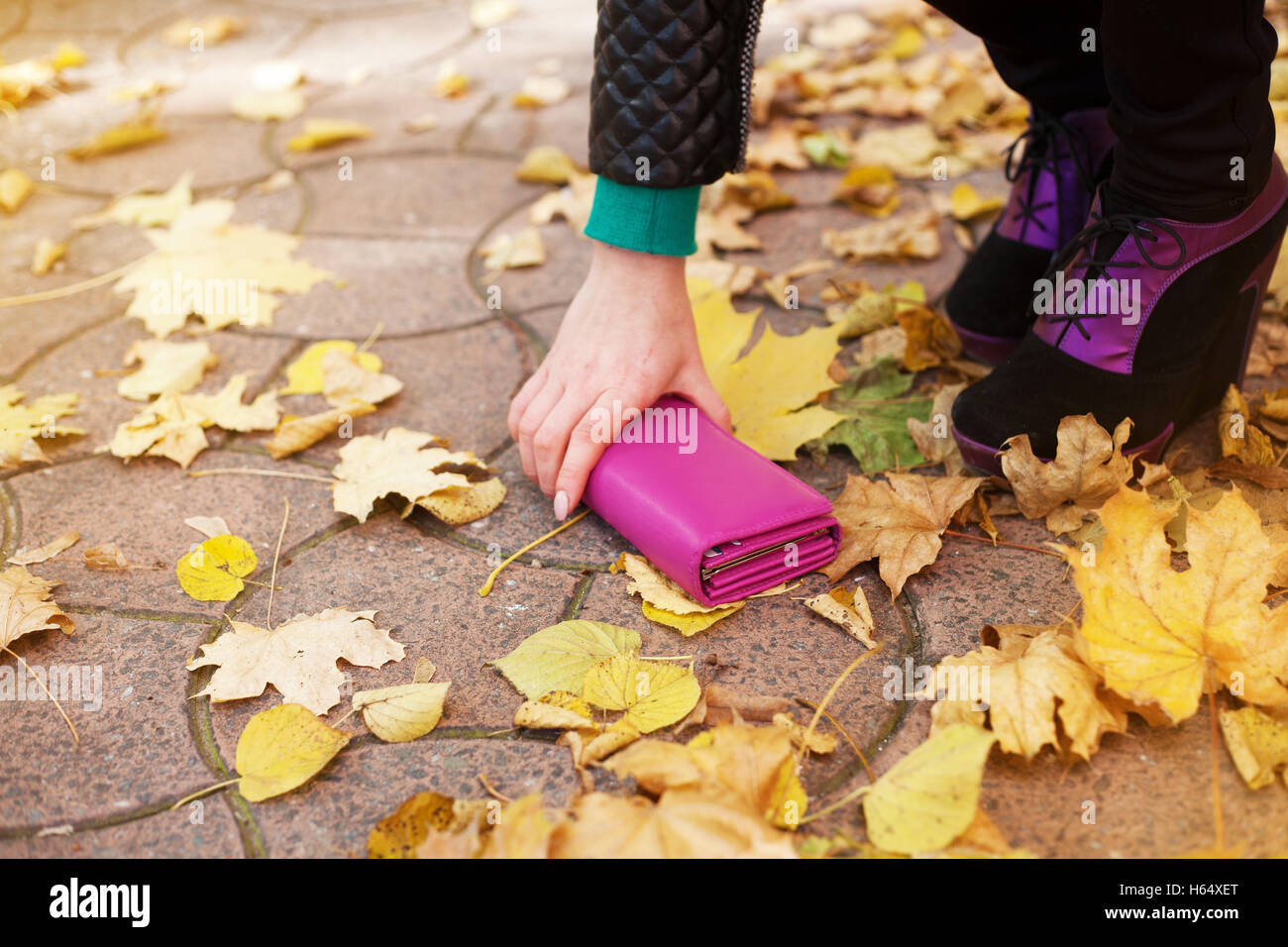 La donna si solleva un portafoglio perso per strada in autunno il giorno Foto Stock