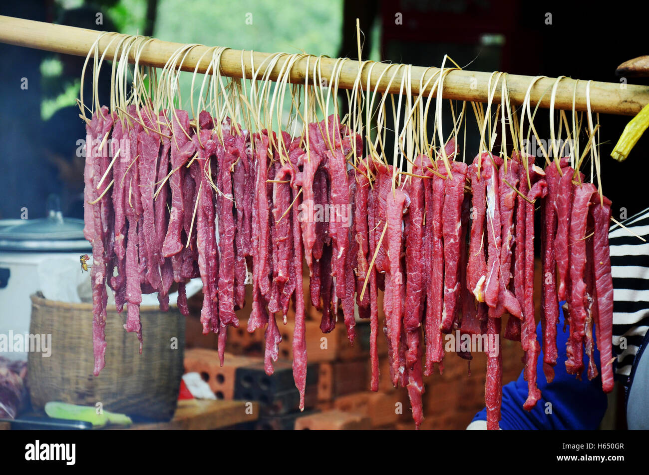 Popolo Lao cottura arrosto di maiale e interiora di maiale alla griglia per la vendita su una vecchia stufa a mercato locale in Laos Foto Stock