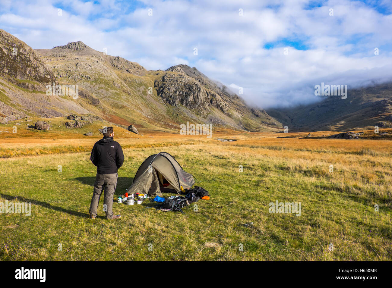 Campeggio selvaggio nella parte superiore della valle Esk nel distretto del lago, un giovane uomo si distingue per la sua tenda Foto Stock