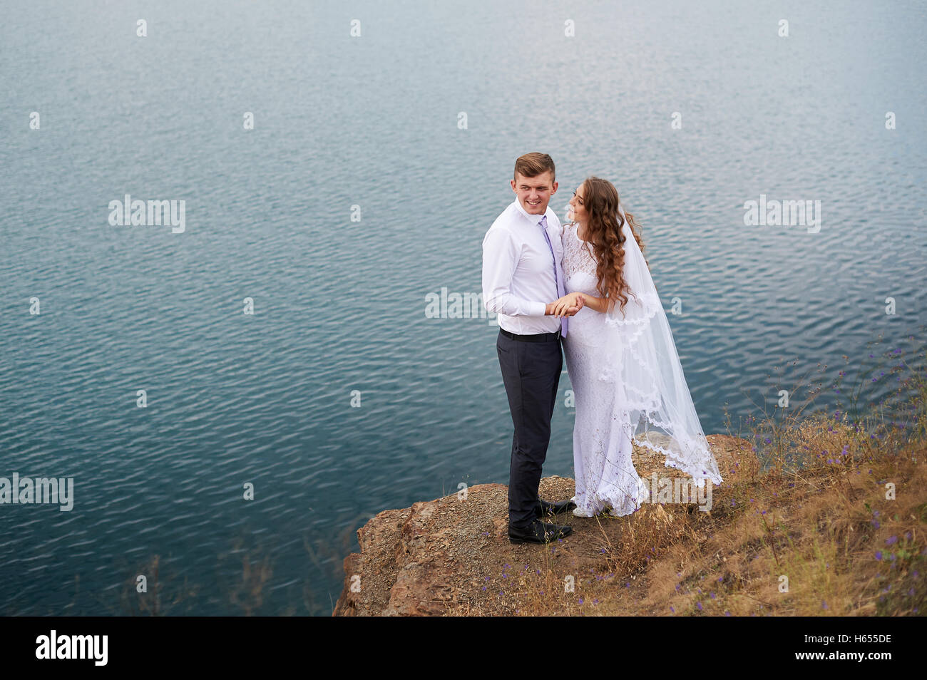 Giovane bella giovane sposa e lo sposo ad un matrimonio a piedi dal lago Foto Stock