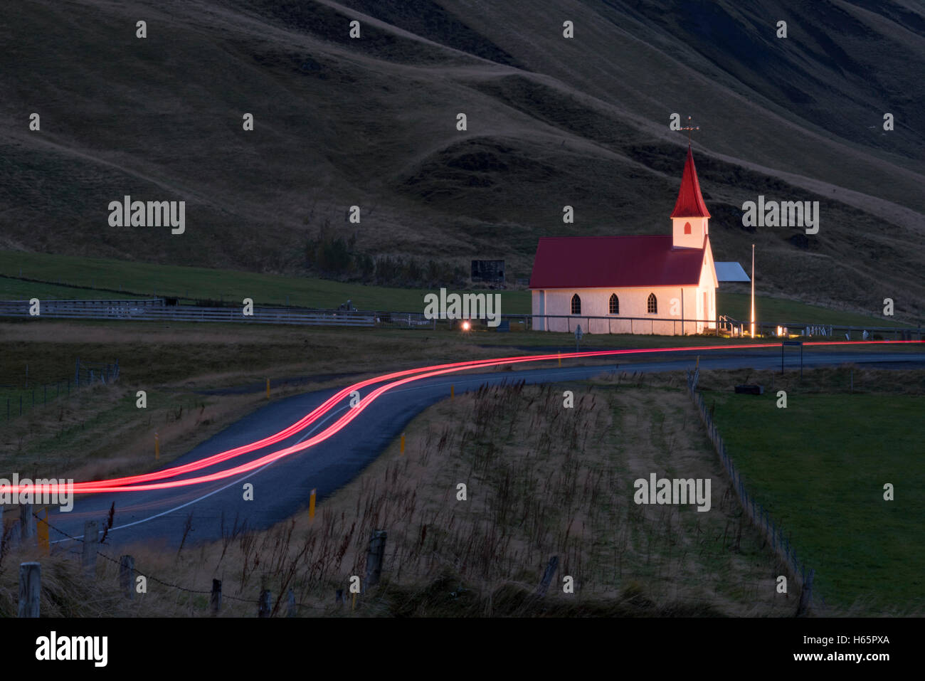 Reynisfjara chiesa illuminata di alba con auto sentieri di luce, Vik mi Myrdal Sud dell'Islanda, dell'Islanda. Foto Stock