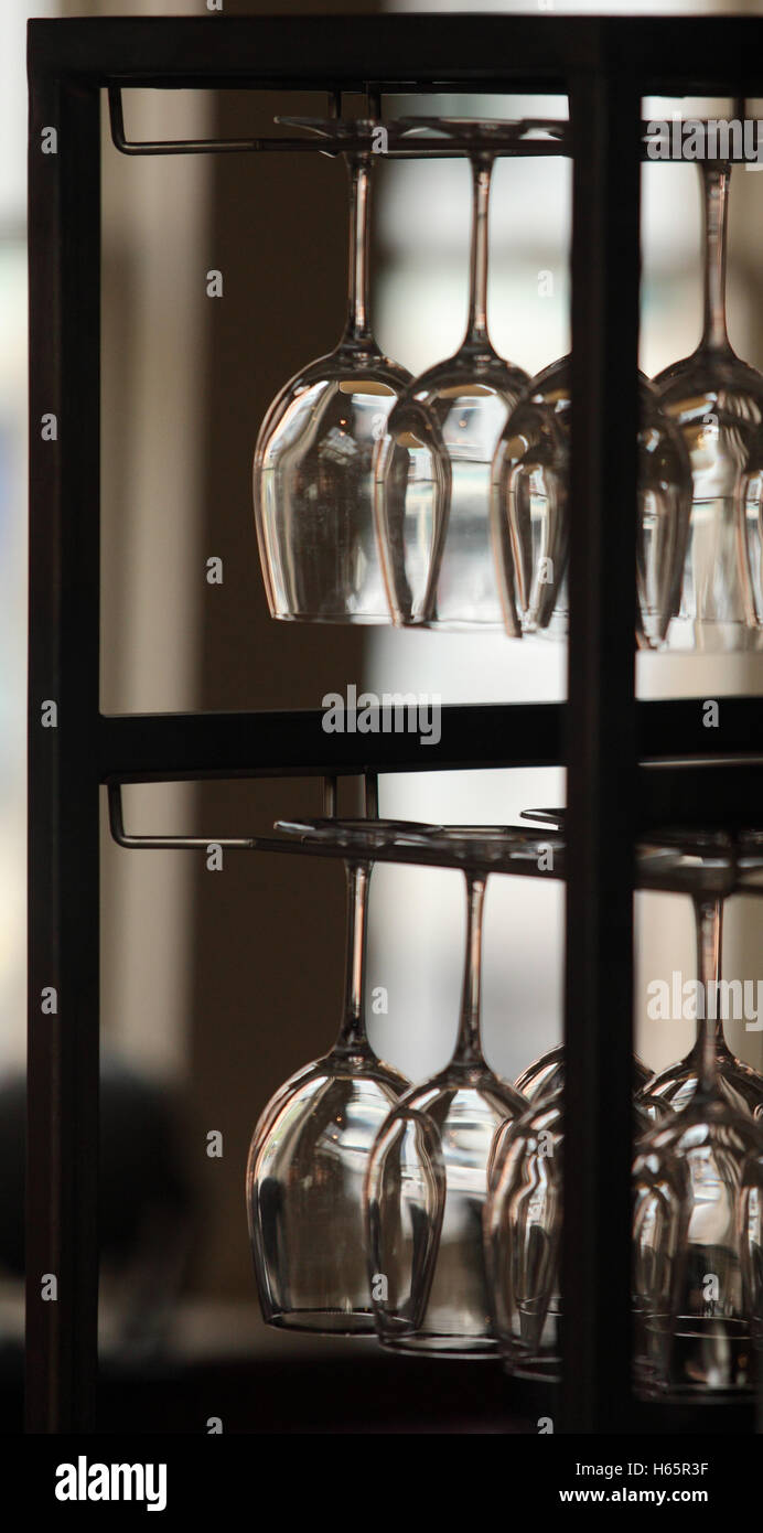 Una fila di sconvolto bicchieri da vino appeso in un rack, retroilluminato Foto Stock