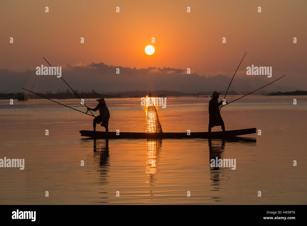 Giovane Asia pescatore sulla barca in azione quando la pesca Foto Stock