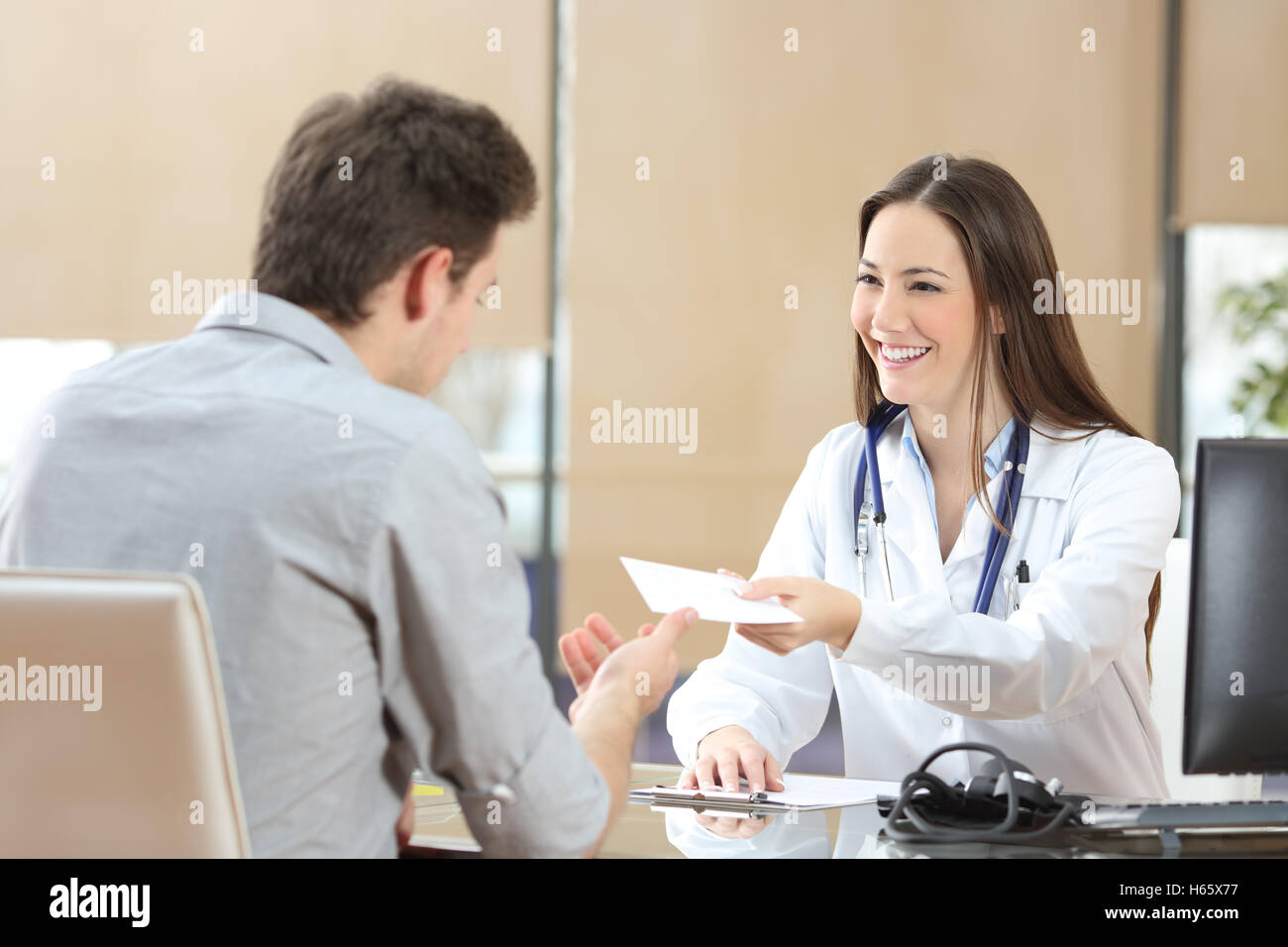 Felice femmina medico dando una prescrizione per il suo paziente in una consultazione Foto Stock