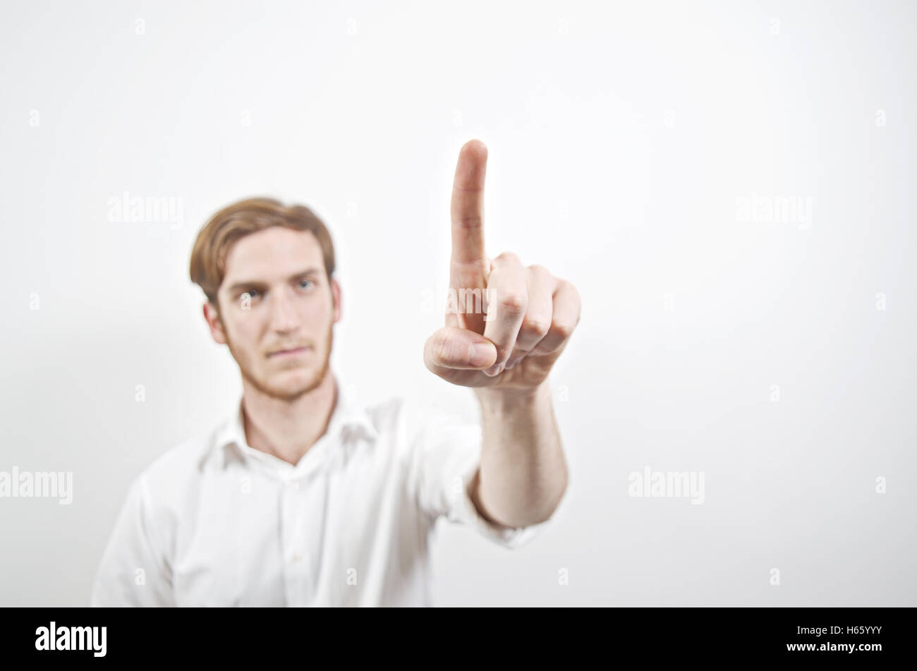 Giovani maschi adulti in maglia bianca rivolta con il suo dito Foto Stock