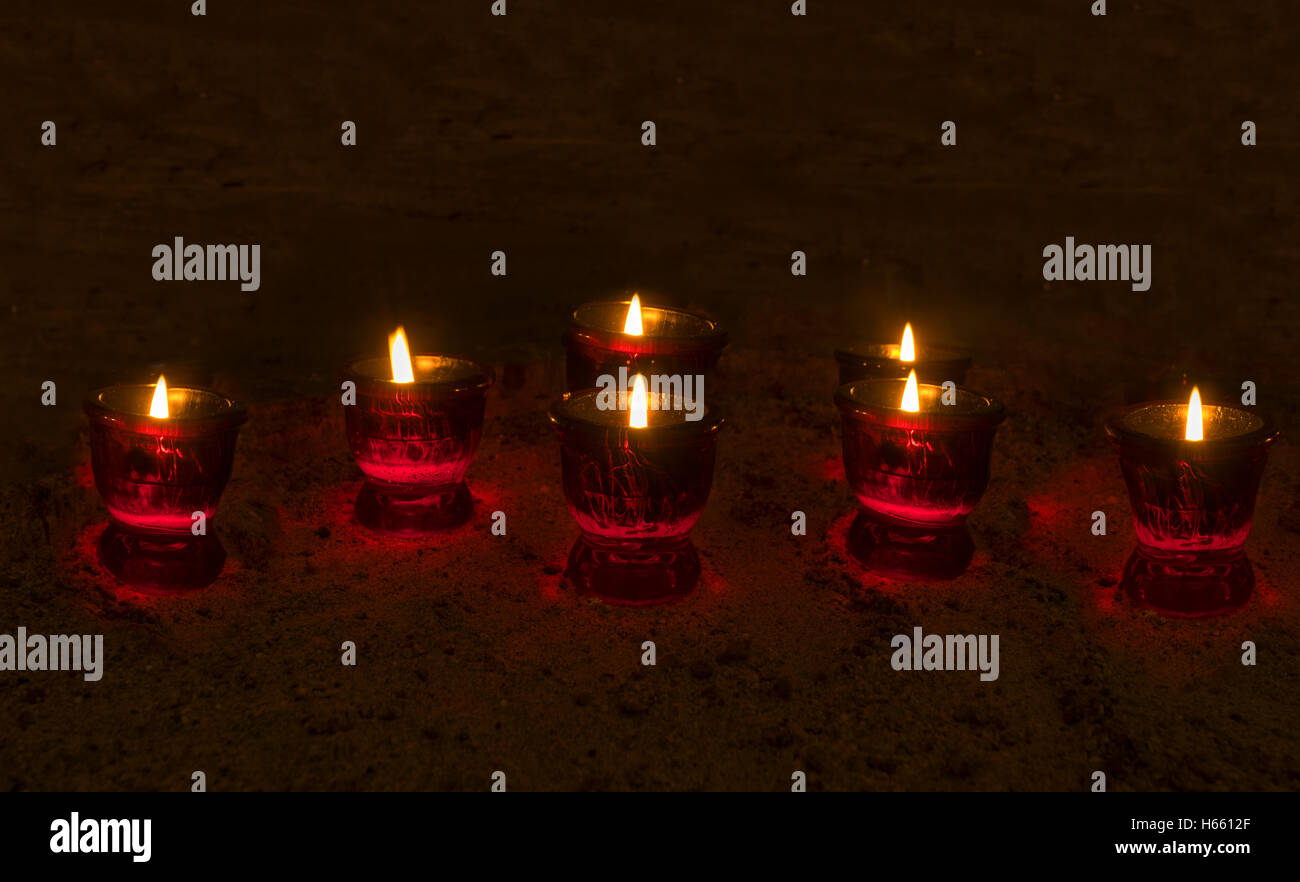 La masterizzazione di candele votive in una stanza buia Foto Stock