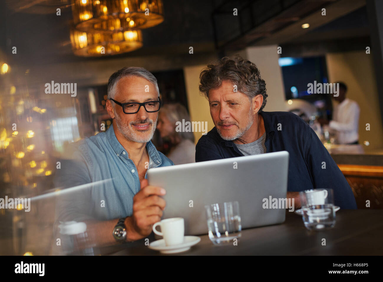 Gli uomini utilizzano computer portatile presso ristorante Foto Stock