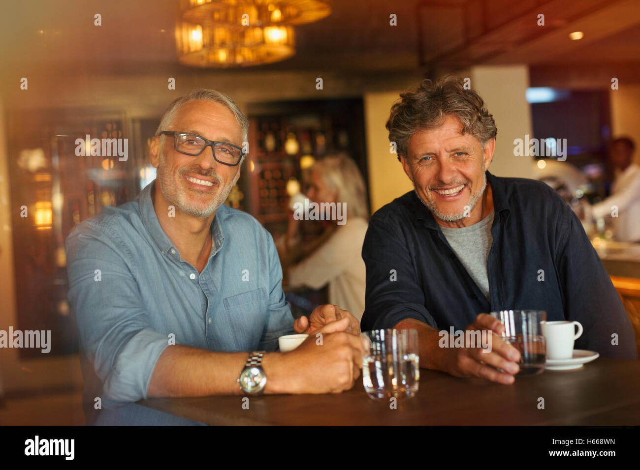 Ritratto uomini sorridenti a bere caffè e acqua a tavola ristorante Foto Stock