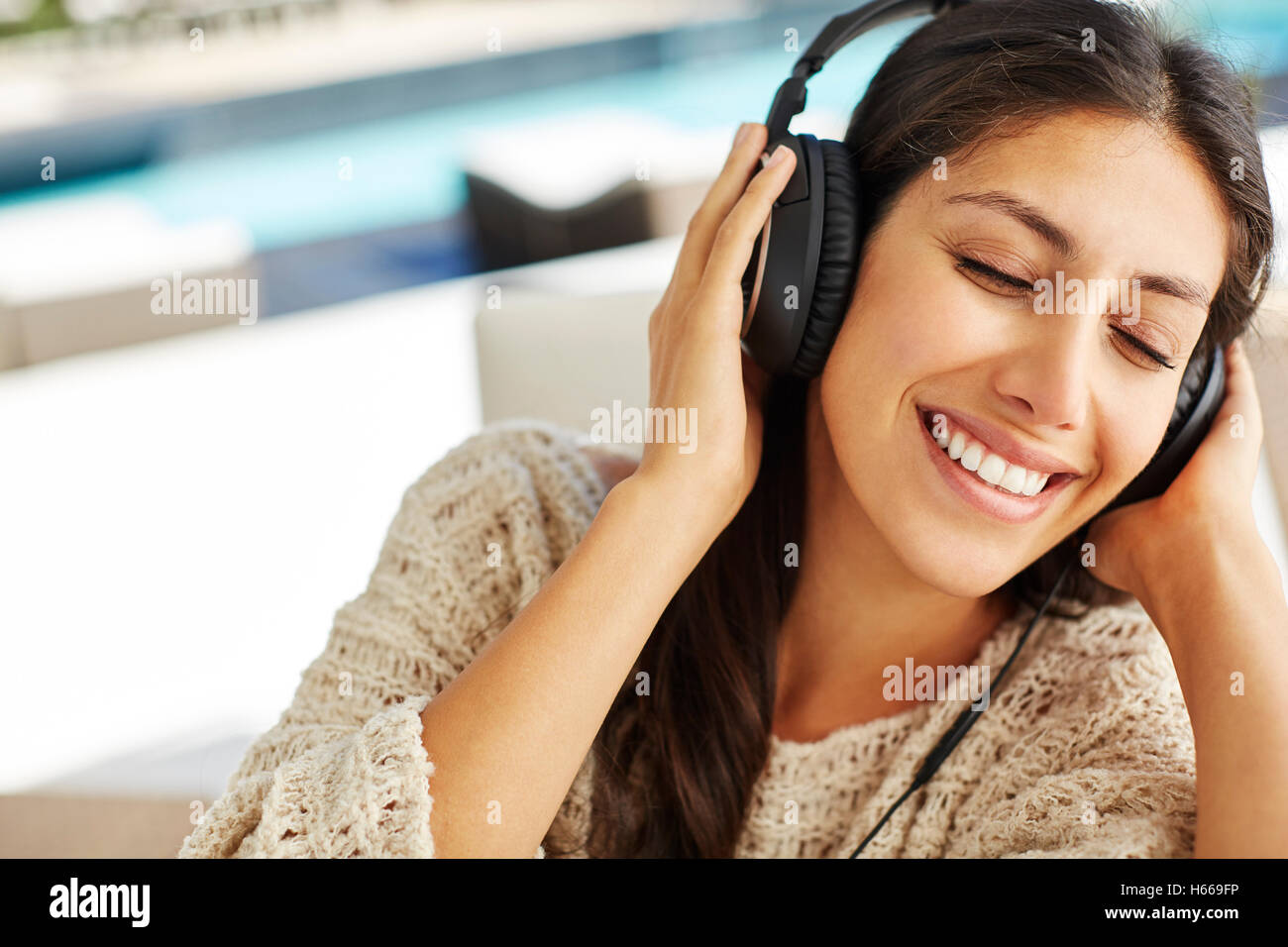 Donna sorridente ascolto di musica con le cuffie e gli occhi chiusi Foto Stock