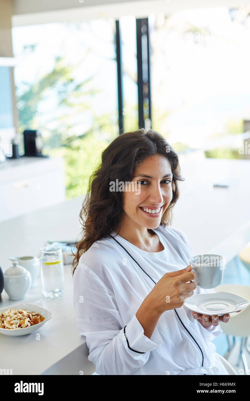 Ritratto di donna sorridente in accappatoio di bere il caffè la mattina in cucina Foto Stock