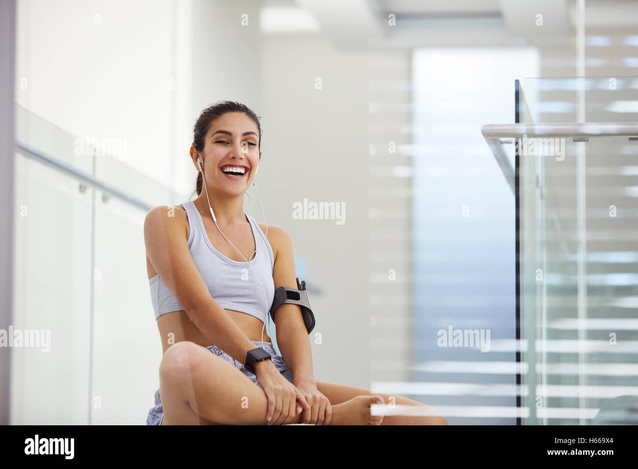 Ritratto di ridere donna l'ascolto di musica con cuffie post allenamento Foto Stock