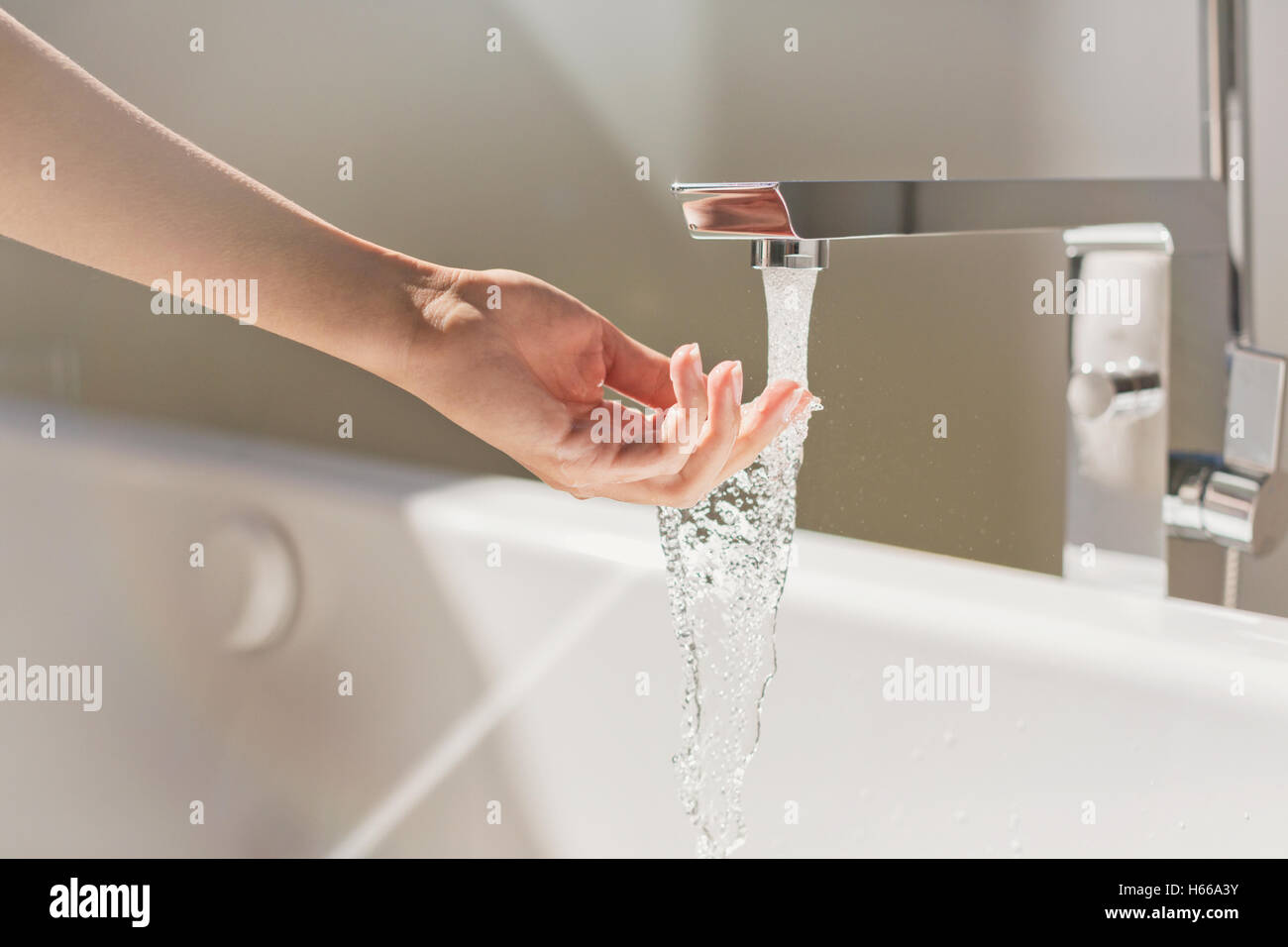 Donna di toccare acqua dalla vasca da bagno moderno rubinetto Foto Stock