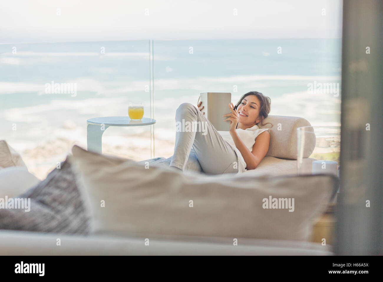 Donna lettura rilassante libro sulla chaise lounge sul balcone di lusso con vista oceano vie Foto Stock