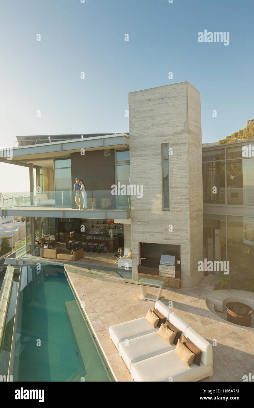 Matura in piedi sul soleggiato e lusso moderno home vetrina balcone su lap pool Foto Stock