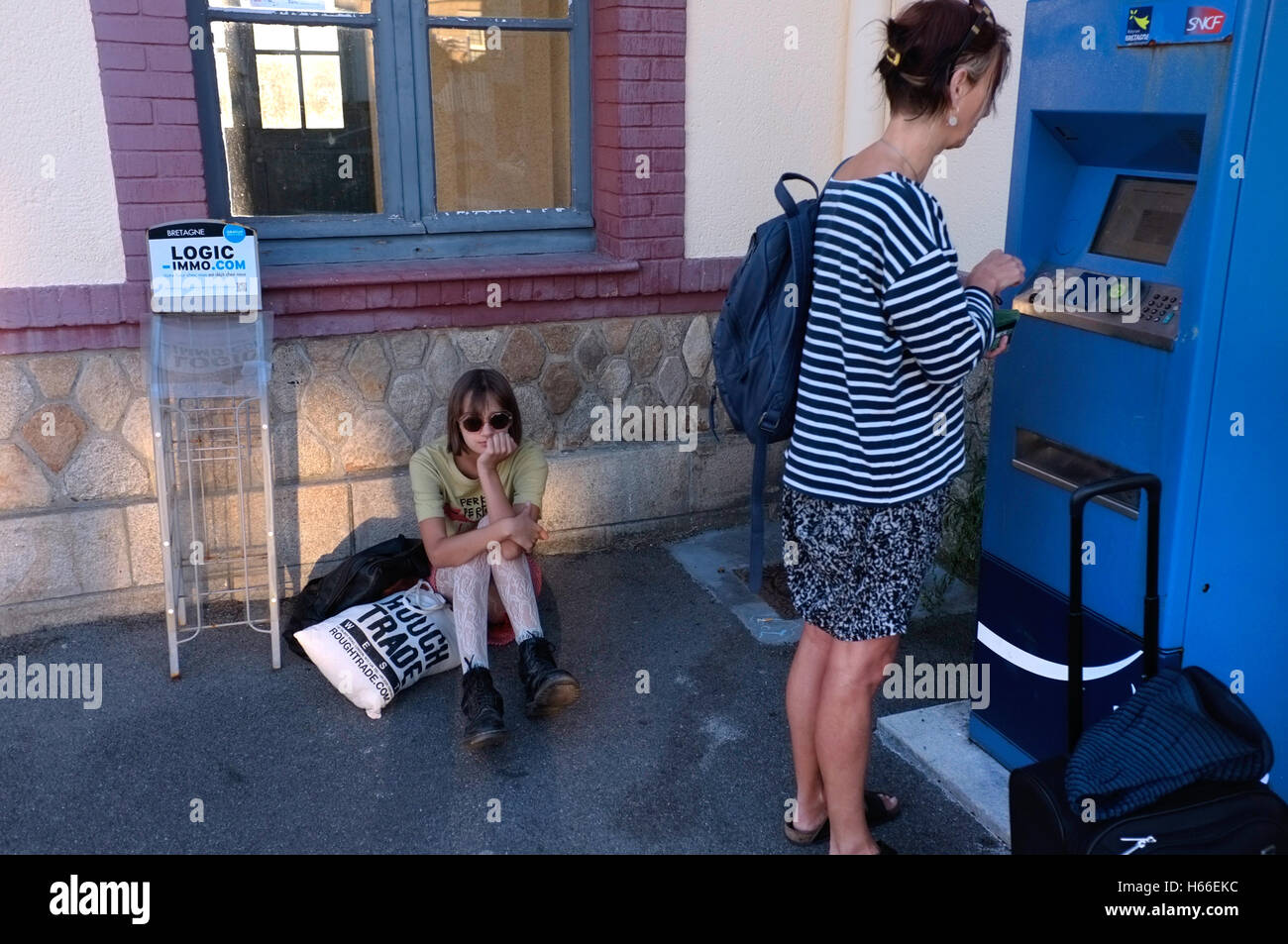 Una madre compra un biglietto del treno per mentre la figlia si siede annoiato. Foto Stock
