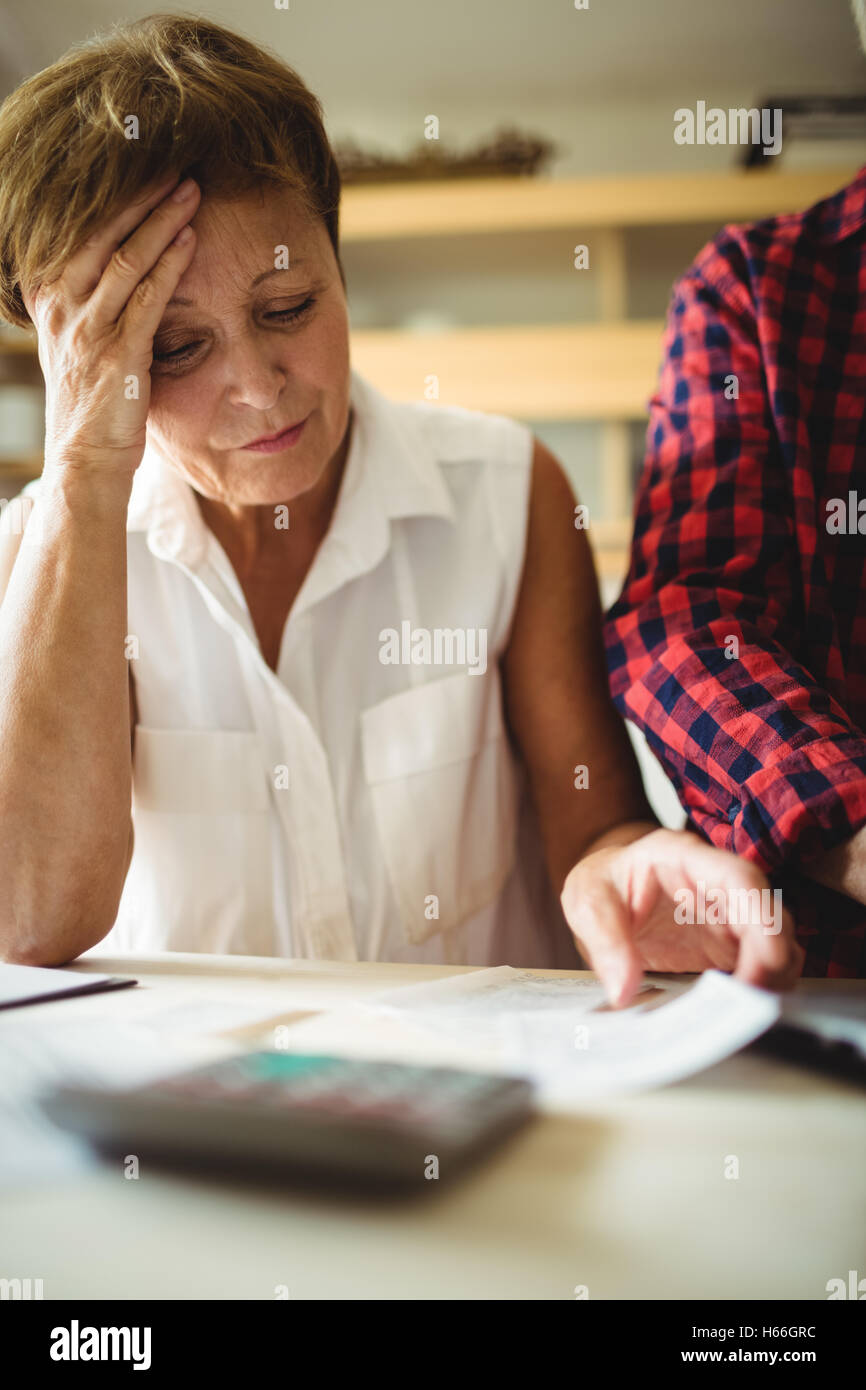 Preoccupato senior donna guardando le bollette Foto Stock